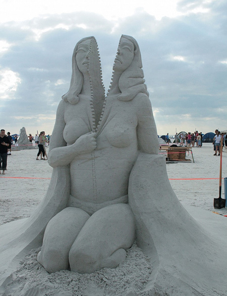 Sand sculpture of a woman zipping herself open