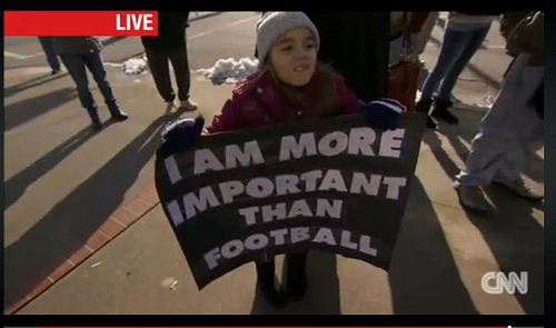 Young girl holding a sign that says I am more important than football