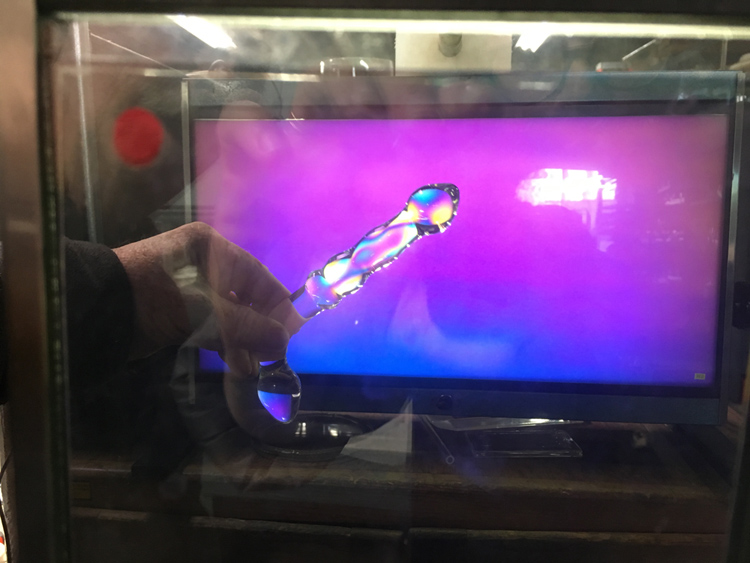 A glass dildo under a polariscope showing rainbow colors