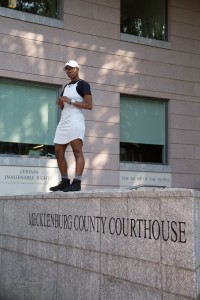 glo Merriweather standing on top of a stone wall that says Mecklenburg County Courthouse