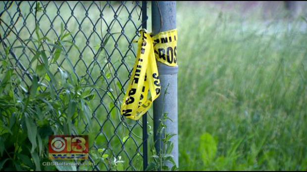 Police tape hangs off a fence.