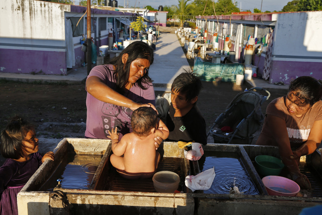Diaz Matia bathes her 9-mo-old son where people wash dishes and clothes in a government-run farm worker camp in Isla del Bosque, Sinaloa, Mexico.