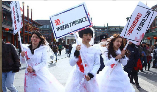 Li (left) and Wei (right) dress up in bloodstained wedding gowns to raise awareness

on domestic violence in China. Their signs: “Why are you still silent about intimate 

violence around you?” and “Love is not an excuse for violence”. (Source: artintern.net)