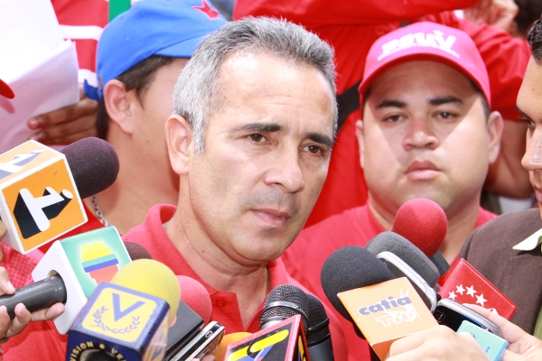 Freddy Bernal, a man with short grey hair, wearing a red polo shirt and in front of press microphones