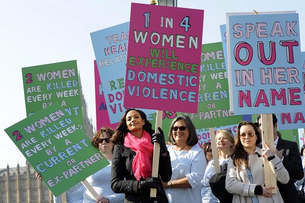 Image of women carrying signs at a protest that read "1 in 4 women will experience domestic violence"