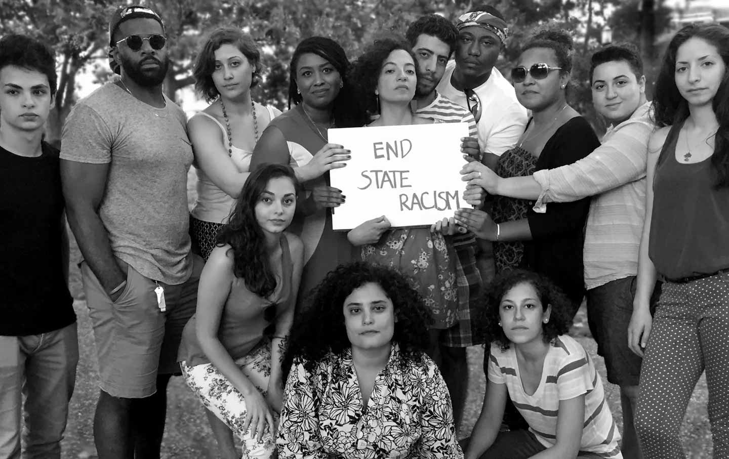 A group of Black and Palestinian organizers hold a sign saying end state racism.
