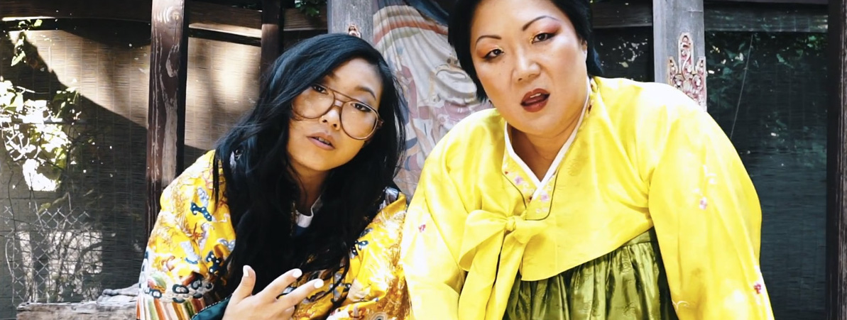 A still from the music video, Margaret Cho and Awkwafina pose in yellow kimonos.