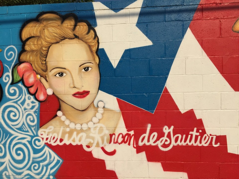 A mural with the Puerto Rican flag as background and a Heroina in the foreground