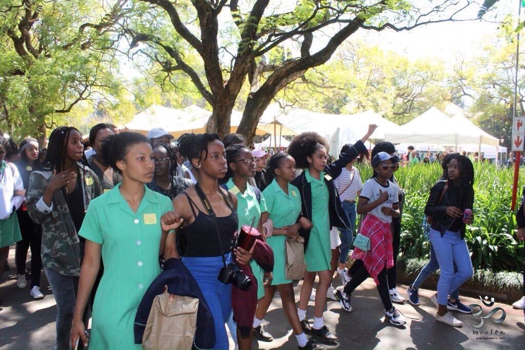 Girls walk in a protest line in green school uniforms