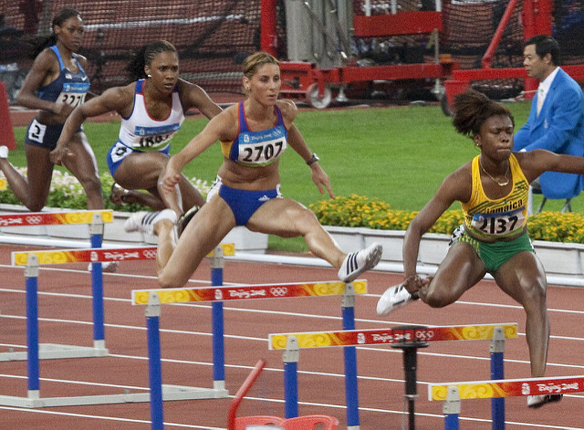 Three olympian women compete in hurdles
