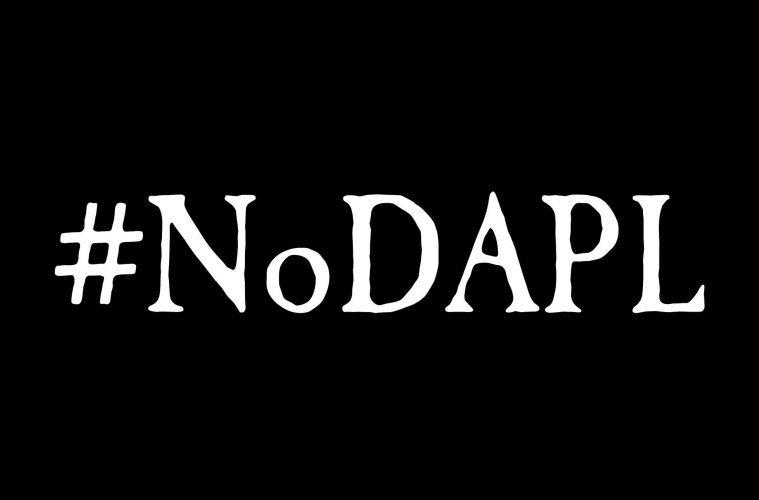 "NoDapl" with a hashtag is written across a black background and white letters