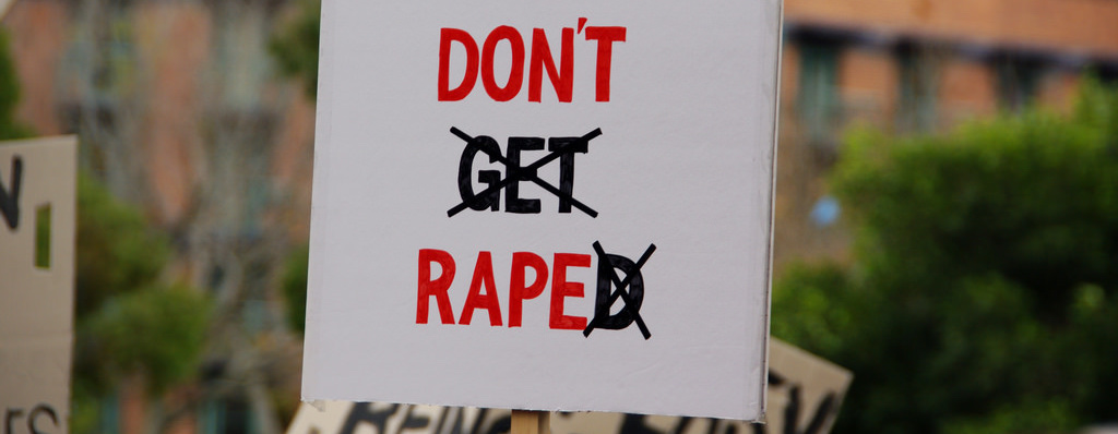 Protest sign reading "Don't get raped," with "get" and "ed" crossed out to read "Don't rape."