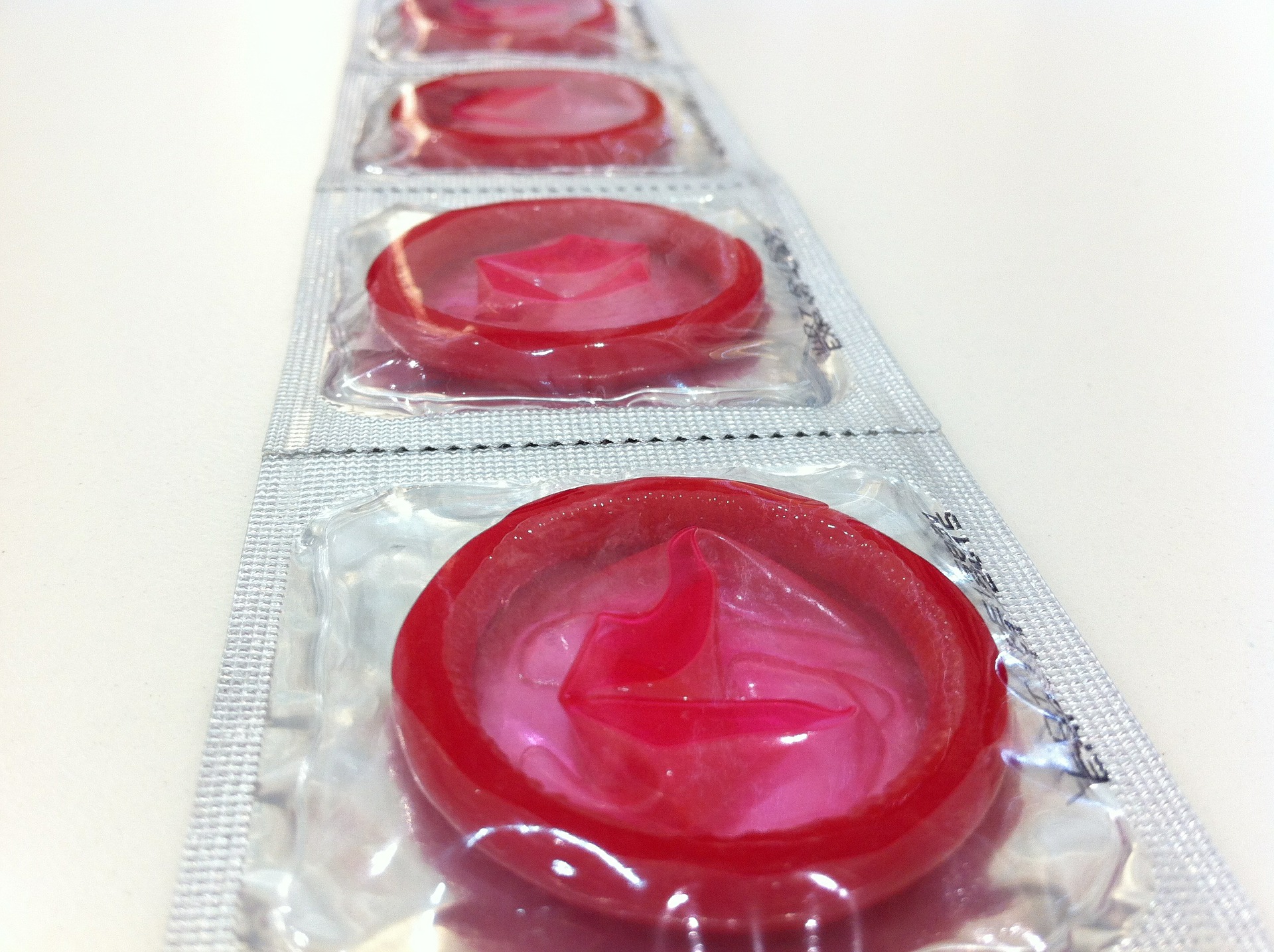 Pink condoms laid out in their wrappers